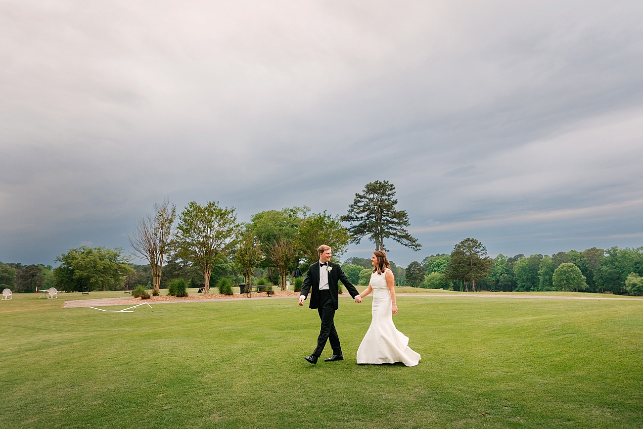 Bride and groom walking under a dramatic sky on their wedding day